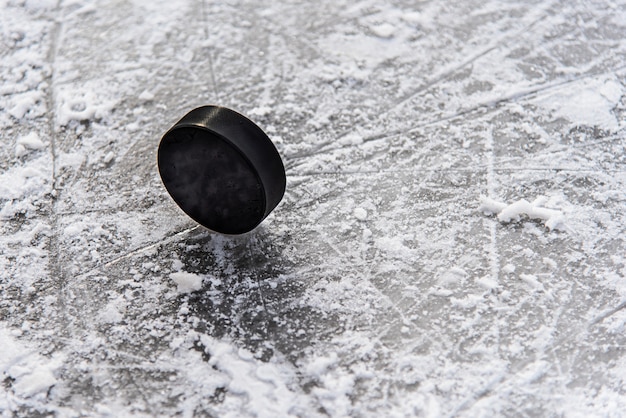 Hockey puck lies on the snow close-up