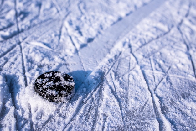 Hockey puck lies on the snow closeup