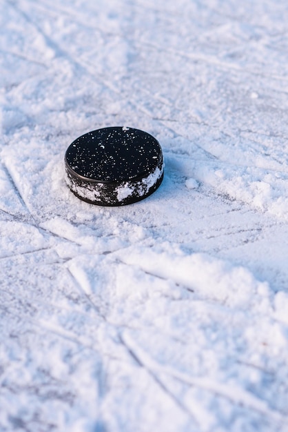 Photo hockey puck lies on the snow closeup