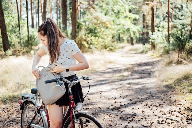 Hoe in te pakken voor fietstocht fietstochten checklist jonge vrouw met rugzak fiets in dennen