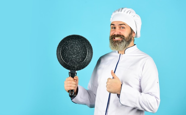 Hoe koken. Keukengerei. Gezond eten koken. lekker gerecht koken. bebaarde man houdt koekenpan vast. Koken in pot. voor het bereiden van voedsel. Bebaarde man koken in de keuken. culinair en keuken.