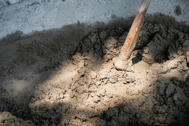 Мотыга смешивает цементный песок и воду в ведре