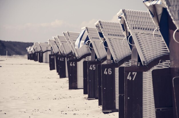 Foto hoedige strandstoelen op zand tegen de lucht