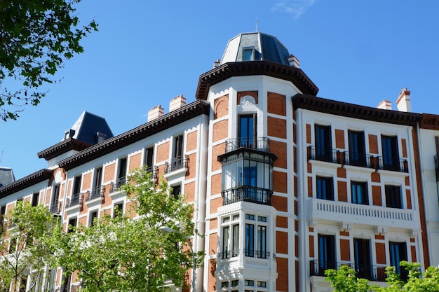 Hoek van klassiek gebouw met metalen balkons en ramen verlicht door de zon in het centrum van Madrid, Spanje