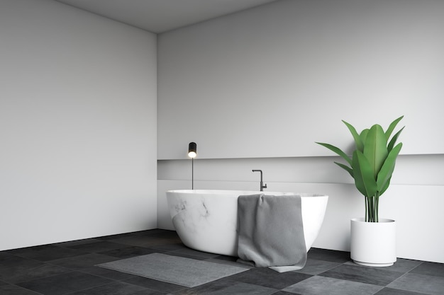 Hoek van moderne badkamer met witte muren, zwarte tegelvloer en witmarmeren badkuip met handdoek eraan. 3D-weergave