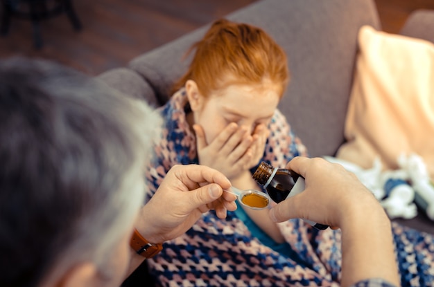 Hoest medicijn. Selectieve focus van een lepel met hoestmengsel in mannelijke handen