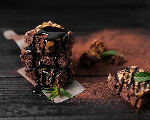 Foto hoge hoek chocoladesiroop gegoten over toren van chocolade noten brownies op dienblad