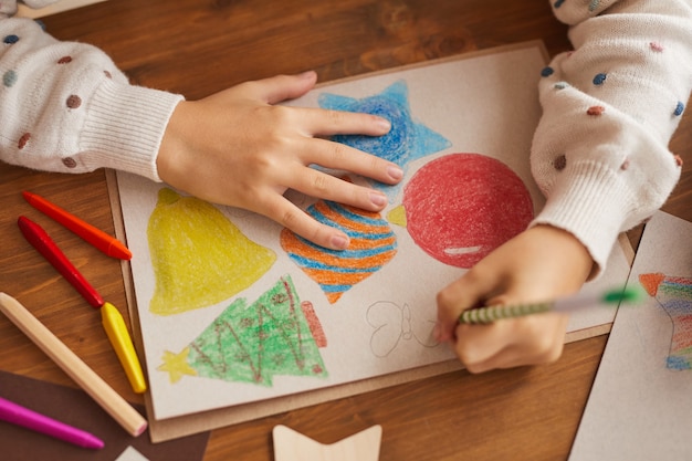 Hoge hoek close-up van meisje tekening kerstkaarten en decoraties op school, kopieer ruimte