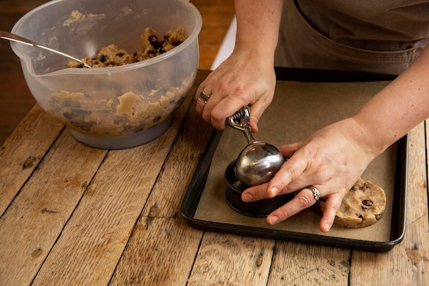 Hoge hoek close-up van persoon die aan houten tafel staat en chocoladekoekjes bakt