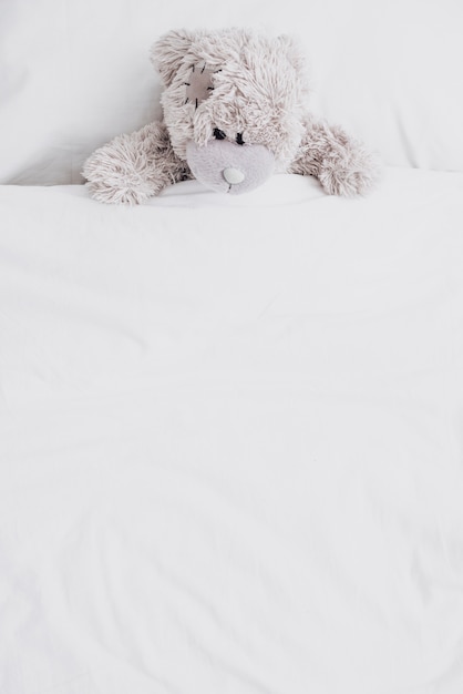 Hoge hoek pluizige teddybeer in bed