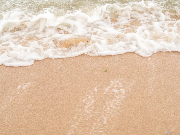 Hoge hoek schot. Close-up, bruin zand van strand- en zeegolven en witte bubbels.