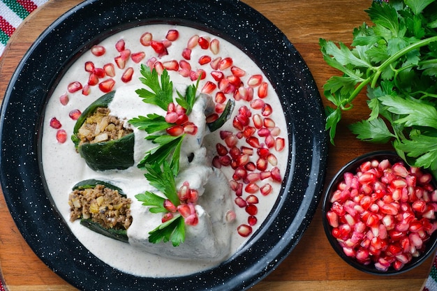 Hoge hoek shot van Chiles en nogada in een plaat op een houten bord op tafel