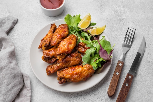 Foto hoge hoek van gebakken kip op plaat met salade en bestek