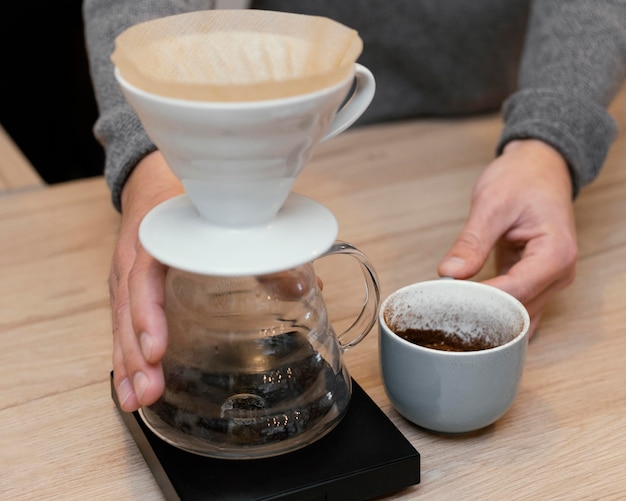 Foto hoge hoek van mannelijke barista met koffiekopje en filter