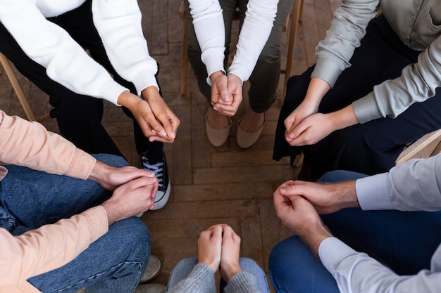 Hoge hoek van mensen handen in een cirkel tijdens een groepstherapie-sessie