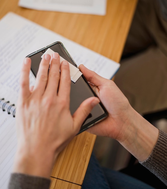 Hoge hoek van vrouw die haar telefoon vóór les ontsmet