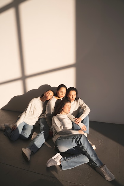 Foto hoge hoek van vrouwen in truien en jeans poseren in raamschaduw