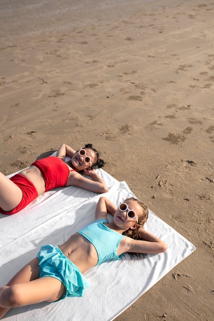 Hoge hoekmeisjes die op het strand liggen