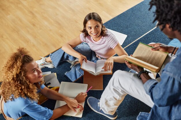 Hoge hoekmening bij diverse groep studenten die samen studeren in bibliotheek focus op lachende jonge vrouw