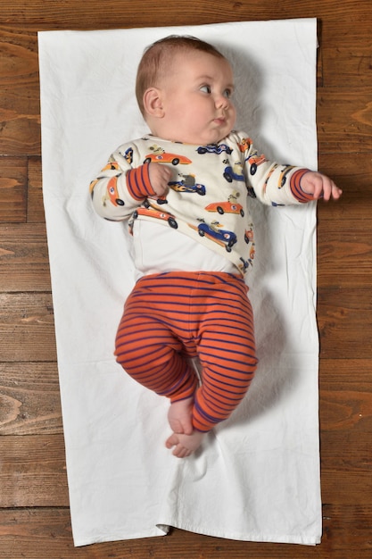 Hoge hoekmening van een baby op de parketvloer gekleed, zijaanzicht