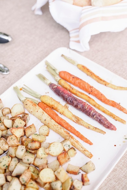 Hoge hoekmening van een bord gegrilde wortelen en aardappelen op een tafel op een tuinfeest