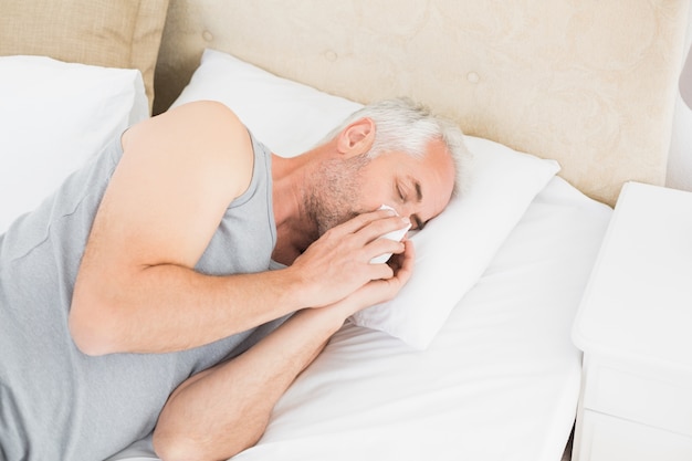 Foto hoge hoekmening van een mens die aan koude in bed lijdt