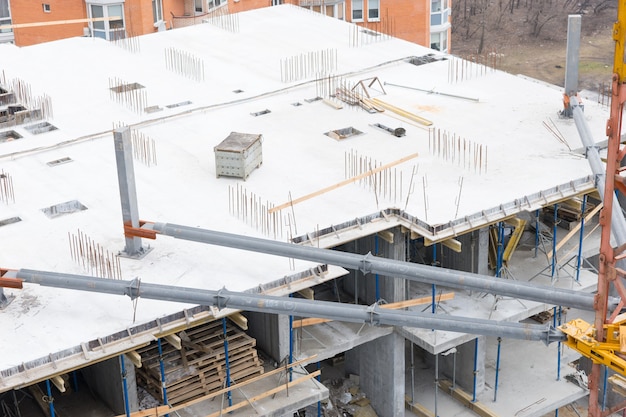 Hoge hoekmening van een nieuw hoogbouwgebouw in aanbouw in een stad met het open betonnen raamwerk van de vloeren gestapeld met hout of timmerhout