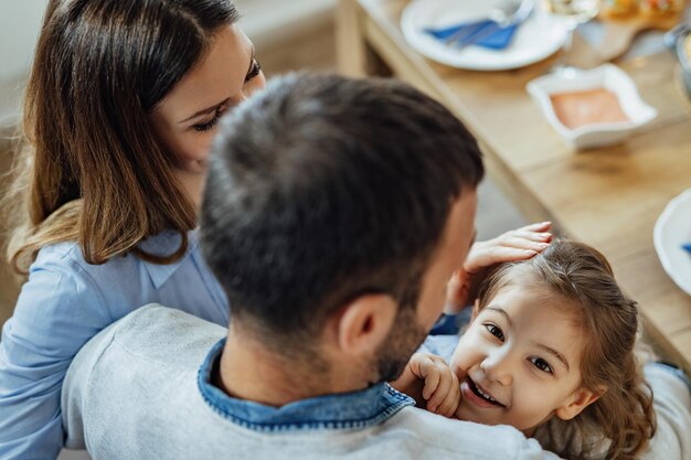 Hoge hoekmening van gelukkige familie die geniet aan de eettafel De focus ligt op een klein meisje dat naar de camera kijkt