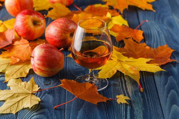 Hoge hoekmening van glas calvados op rustieke houten tafel met appels en autump bladeren