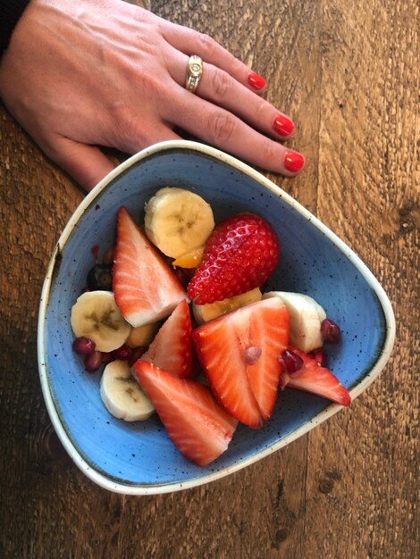 Foto hoge hoekmening van hand met fruit in kom