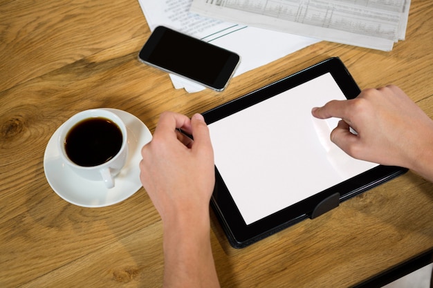 Hoge hoekmening van man handen met behulp van tabletcomputer aan tafel in coffeeshop