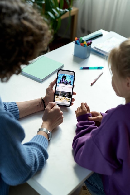 Hoge hoekmening van moeder en haar kind die samen video kijken op smartphone terwijl ze bezig zijn