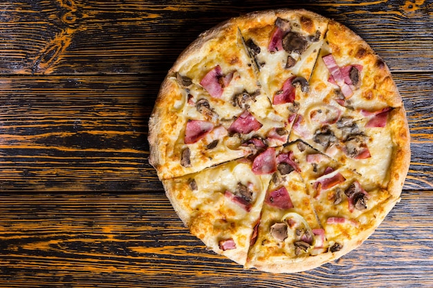 Hoge hoekmening van smakelijke pizza met ham, champignons en ui op houten tafel