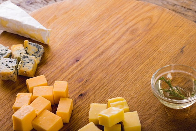 Hoge hoekmening van verschillende kaas met rozemarijn op een houten bord, kopieerruimte