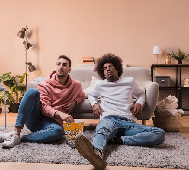 Hoge hoekmensen die op vloer popcorn eten