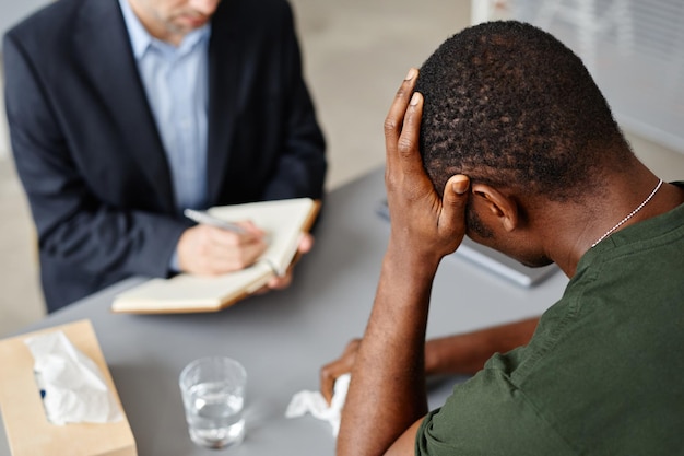 Hoge hoekopname van een jonge afro-amerikaanse man die lijdt aan een psychische stoornis na het ervaren van verschrikkingen