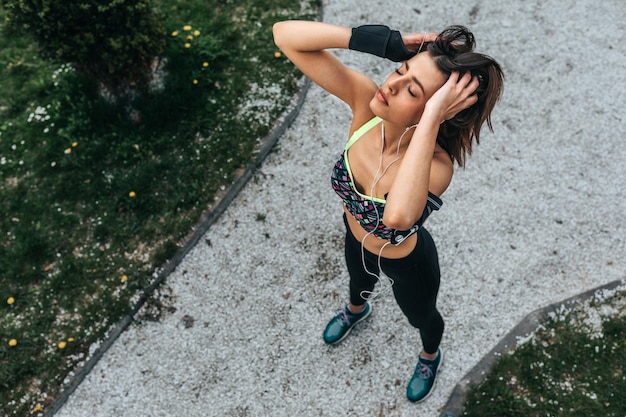 Hoge hoekopname van een jonge sportvrouw die haar haar buitenshuis aanraakt