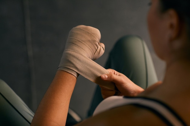 Hoge hoekopname van professionele bokser die haar handen omwikkelt met elastisch verband