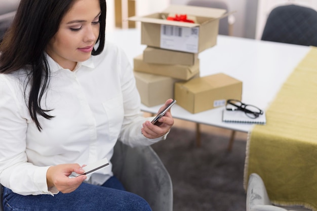 Hoge hoekvrouw die haar telefoon controleert voor een nieuwe aankoop