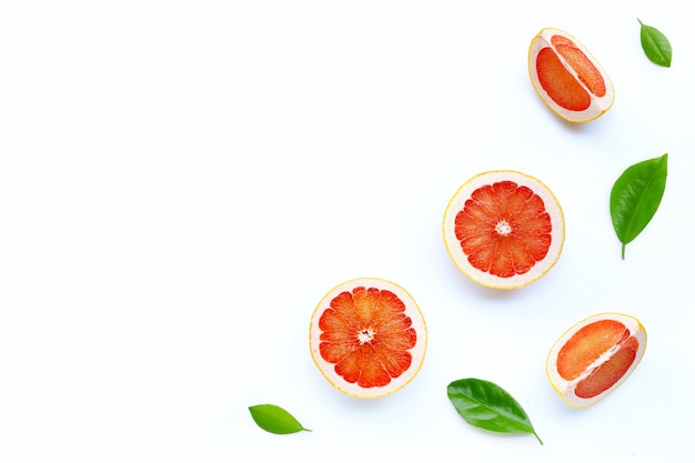 Hoge vitamine C. Sappige grapefruitplakken met groene bladeren op witte achtergrond.