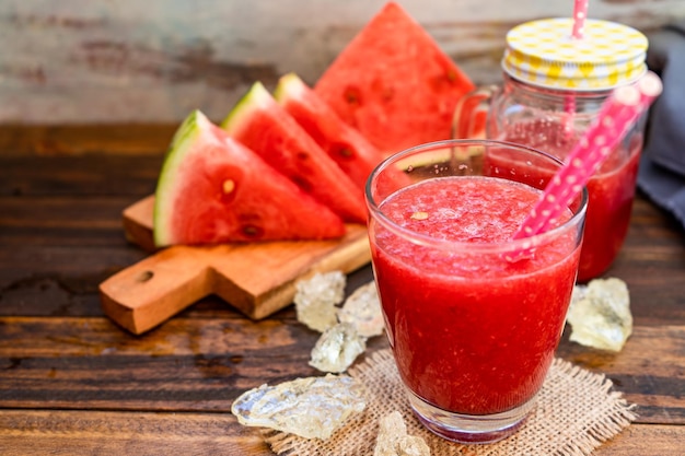 Hoge weergave van een groot glas met een koude watermeloen-smoothie en enkele driehoekjes watermeloen