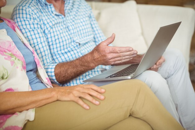 Hoger paar dat laptop in woonkamer met behulp van