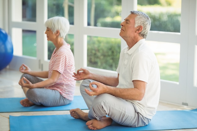 Hoger paar dat yoga op oefeningsmat uitvoert