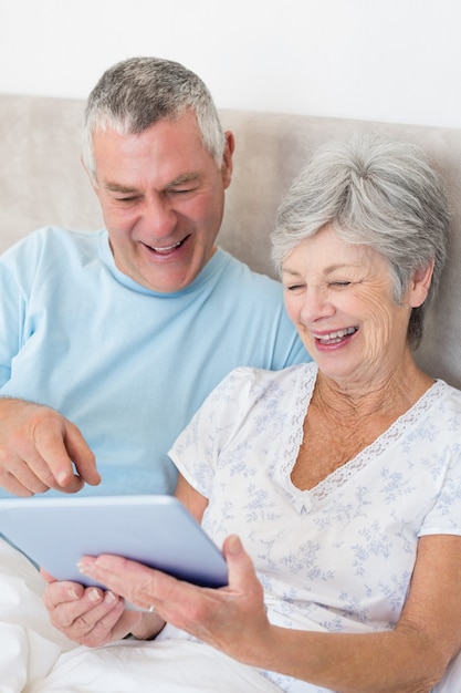 Hoger paar die digitale tablet in bed gebruiken