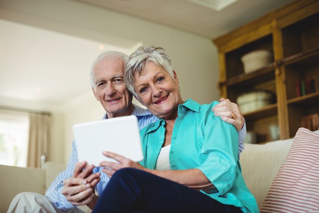 Hoger paar die digitale tablet in woonkamer gebruiken