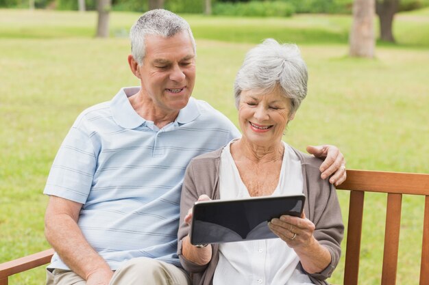 Foto hoger paar die digitale tablet op bank gebruiken bij park