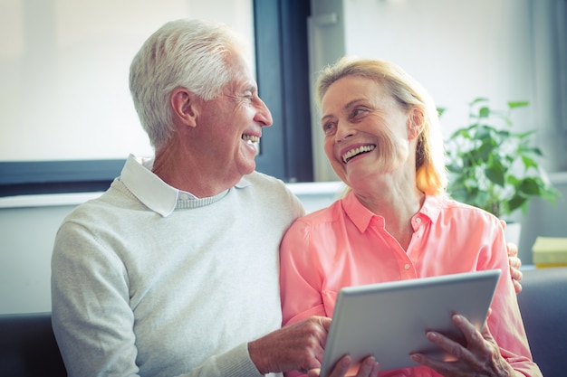 Hoger paar die terwijl het gebruiken van digitale tablet glimlachen