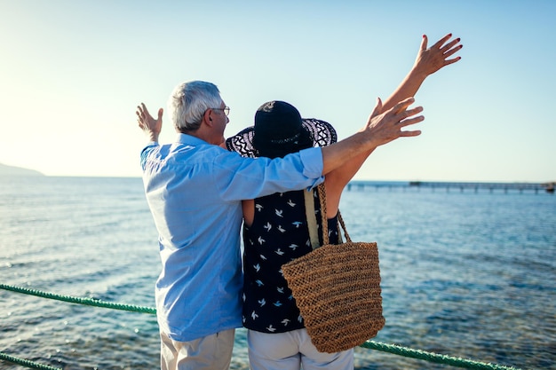 Hoger paar die wapens op pijler door Rode overzees opheffen Gelukkige mensen die vakantie vieren Valentijnsdag concept