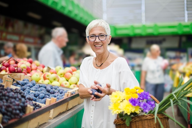 Hoger vrouw het kopen fruit op markt