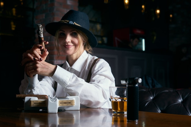 Hogere aantrekkelijke vrouwelijke gangster rokende sigaar over dark in restaurant